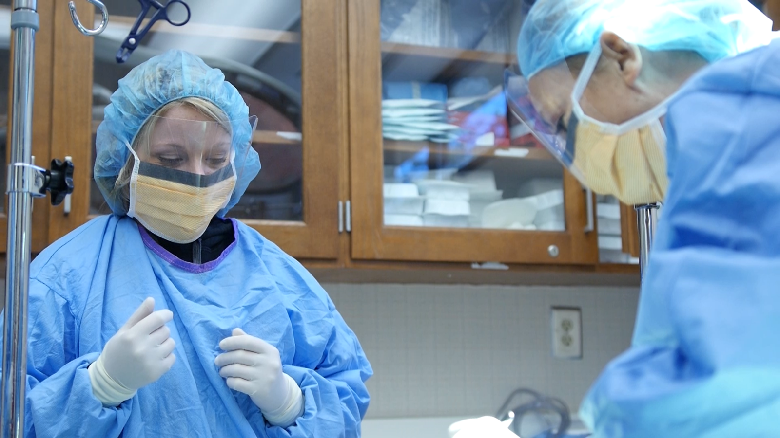 两个学生穿着手术服和口罩练习手术技术.